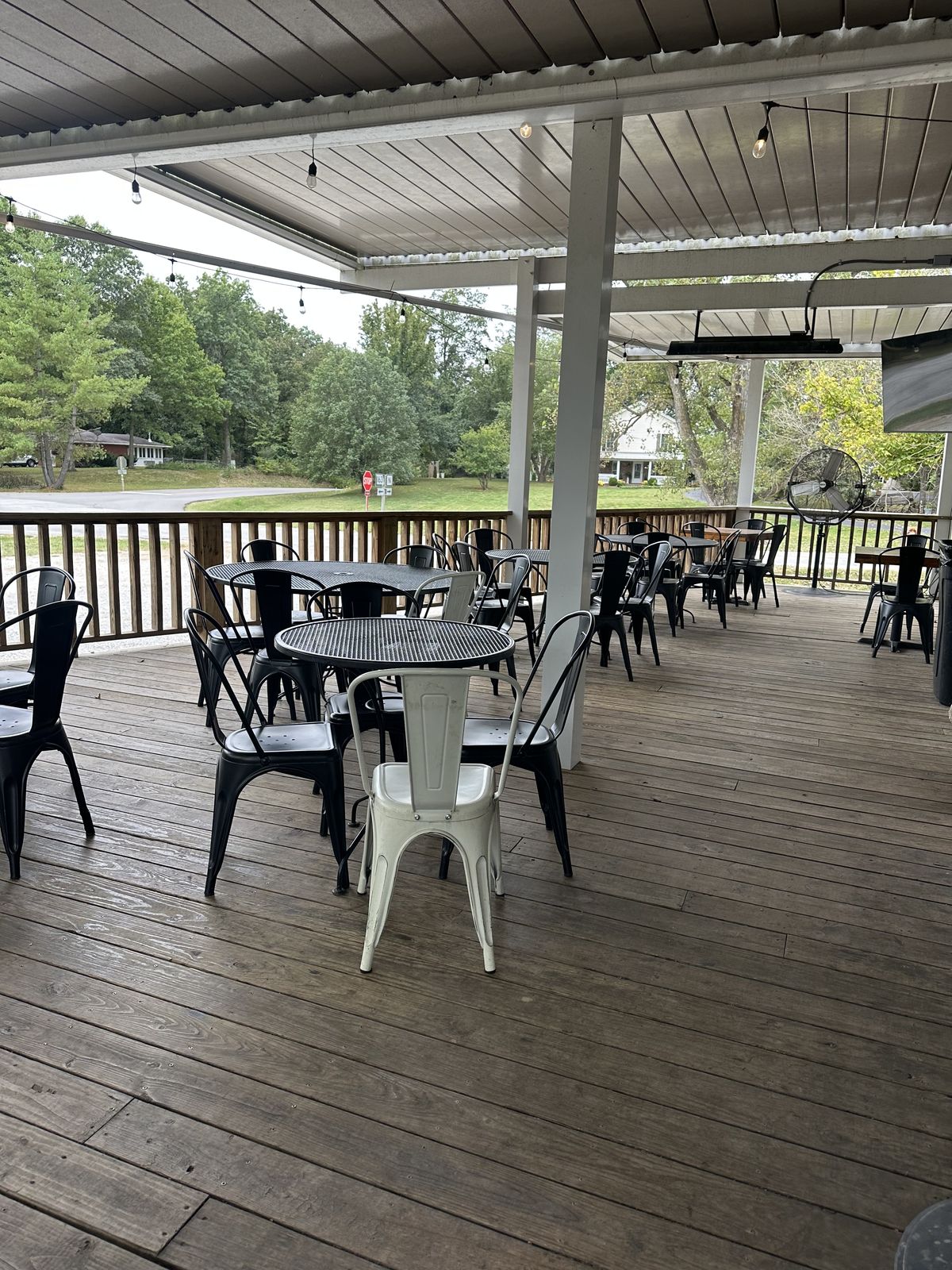 Tables and chairs beneath Pierpont’s covered porch with string lights and radiant heaters