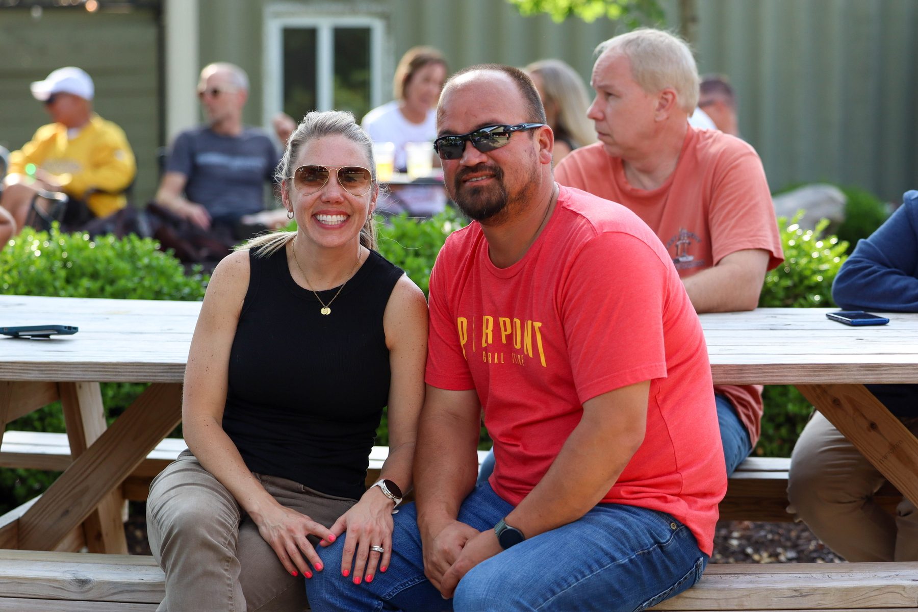 A smiling couple sits together at a picnic table on the Pierpont patio.